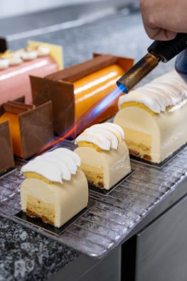 Pâtissier caramélisant des entremets au chalumeau